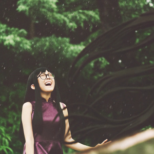Xiaoyu, a joyful young girl with long black hair and glasses, stands amidst an eerie, dark backdrop filled with swirling, fluid-like shadows. She is dressed in a vibrant purple outfit.