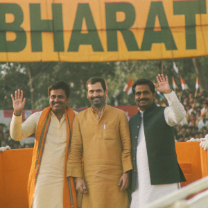 Rahul Gandhi and other Indian politicians in traditional clothing, posing for a photo at a political rally. A large 'Bharat' banner stands behind them.