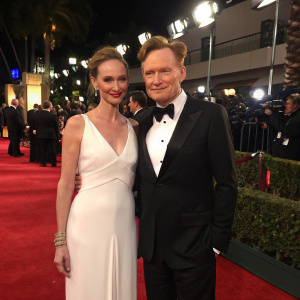 Liza Powel and Conan O'Brien at the Golden Globe Awards. Liza in white dress, Conan in black tuxedo. Red carpet background