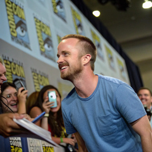 Aaron Paul at Comic-Con, wearing a casual blue t-shirt. Surrounded by fans.