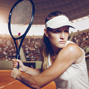 Genie Bouchard, wearing a Nike visor, intensely focused. Playing tennis match, vibrant audience in stadium background
