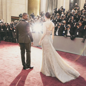 Jamie Foxx and Jessica Biel at the Oscars, posing for photos. Jamie Foxx in sharp black suit, Jessica Biel in shimmering gown. The red carpet behind them, crowded with paparazzi and cameras flashing.