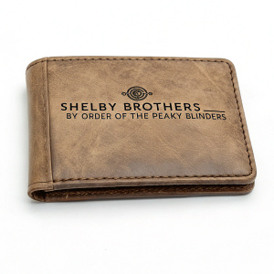 Vintage leather wallet featuring 'Shelby Brothers by Order of The Peaky Blinders' logo. Distressed and etched text. Traditional design. Against clean white background.