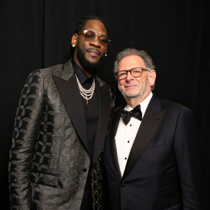 2 Chainz and Sir Lucian Grainge, posing formally. Solid black background, music award show
