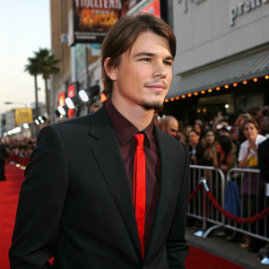Josh Hartnett at the Hollywood premiere of 'Halloween H20: 20 Years Later'. Dressed in a black suit with a red tie. Crowds of fans and paparazzi in the background.