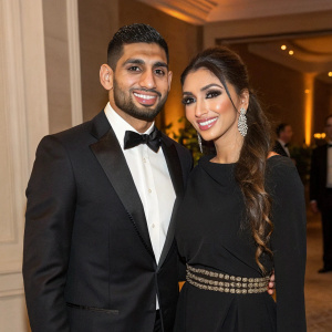 Amir Khan and Faryal Makhdoom attending a gala dinner. Amir in a black tuxedo, Faryal in a black dress with a belt. Both smiling.