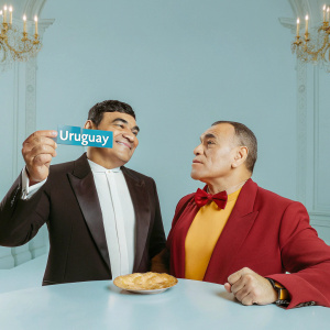 Diego Maradona and Cafu, both former football stars, are attending a gala event. Maradona holds a blue card that says 'URUGUAY'. Both are dressed in formal wear.