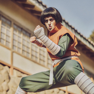 Rock Lee, from Naruto Shippuden, in intense fighting stance. Standing in front of a bright blue backdrop.