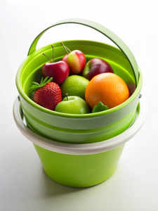 a green folding bucket with white sides and fruits inside