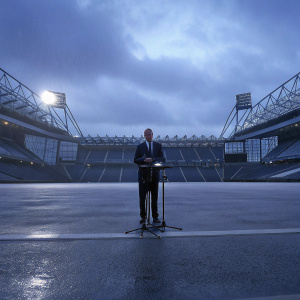 Ralf Rangnick, in a business suit, giving a press conference at Old Trafford stadium.