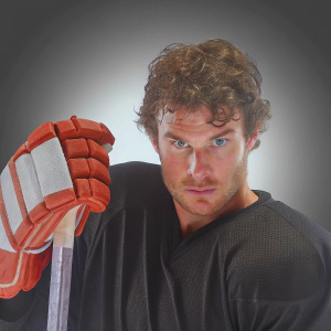 Brayden McNabb, hockey player, intense stare, curly hair, black jersey. Against black backdrop, promotional shot