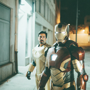 Tony Stark, in his Iron Man suit, and War Machine in his golden armor, standing on a dimly lit street at night. Both looking serious and ready for action