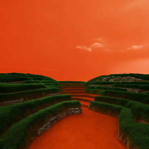 Ancient Inca ruins of Sacsayhuaman, located high in the Andes mountains near Cusco, Peru. Overgrown with lush green vegetation and winding pathways. A serene sky with scattered clouds above.