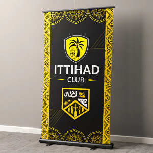 A promotional banner for Ittihad Club featuring a bold black background. The design is adorned with vibrant yellow borders and intricate Arabic text. Logos and emblems are prominently displayed. Modern and graphic, the poster catches the eye.
