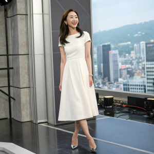 Lee Da-Hee, Asian actress, standing alone in studio. She wears a simple white dress. Cheerful smile, set against an urban backdrop.