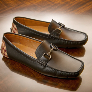 Burberry men's black leather driving shoes with white background. Classic plaid pattern and buckle closure. Elegant and sleek design.
