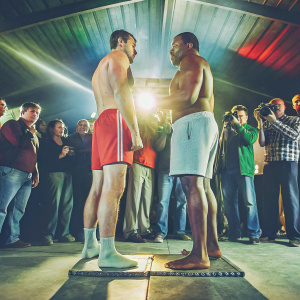 Carl Froch and Andre Dirrell at a UFC weigh-in event. Both boxers are dressed in plain shorts and athletic attire. A crowd of fans and officials are visible in the background.