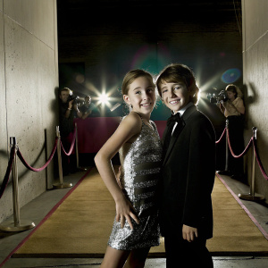 Noah Cyrus and Frankie Jonas at a glitzy award show. Neon pink and blue backdrop, vibrant and energetic atmosphere