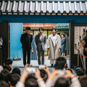 Park Hee-Soon, Kim Myung-Min, Jang Dong-Gun, and Lee Jong-Suk at a bustling Korean film festival. The actors stand in front of a vibrant film poster backdrop. Crowds of fans and photographers surround them, capturing the moment.