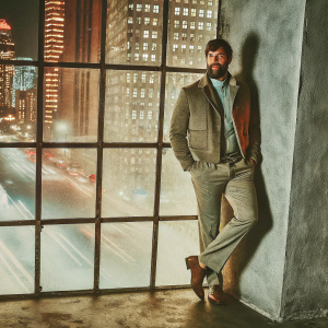 Alisson Becker, the goalkeeper, with a beard, posing for a magazine photo shoot. City skyline background.