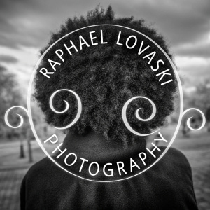 Logo for Raphael Lovaski Photography. Black individual with curly hair, set against a monochrome background. The text swirls elegantly around the image, creating a visually stunning and artistic effect.