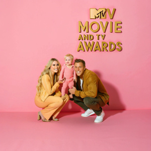 Heidi Montag, Spencer Pratt, and Gunner Pratt at a glitzy Hollywood event. They pose with a backdrop featuring the MTV Movie and TV Awards logo. Heidi is kneeling, Spencer is crouching, and Gunner stands between them, all smiling for the camera.