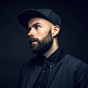 Woodkid, aka Yoann Lemoine, intense stare. Dark background, studio photo