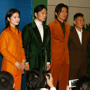 Charlene Choi, Tony Leung Chiu-wai, Felix Chong, and Andy Lau Tak-wah at a press conference. Dressed in formal wear. Blue backdrop. Audience holding smartphones