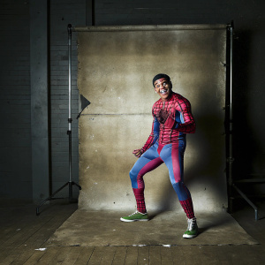 Young Miles Morales, Hispanic, in vibrant Spider-Man suit, exuding joy. Against plain white backdrop, dynamic pose, photo-realistic quality