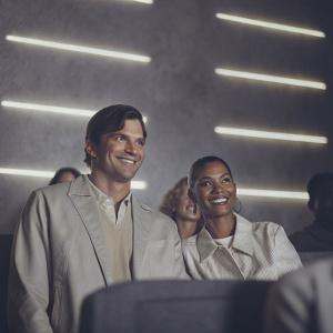 Ashton Kutcher and Beyoncé, smiling, at a private screening of a film at Universal Studios. Neon lights and blurred audience in background