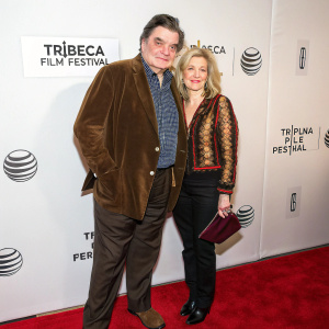 Oliver Platt and Mary Camilla Bonsal Campbell at the 2015 Tribeca Film Festival. Oliver in brown velvet blazer, Mary in richly patterned top. Standing on red carpet with white backdrop featuring logos and text.