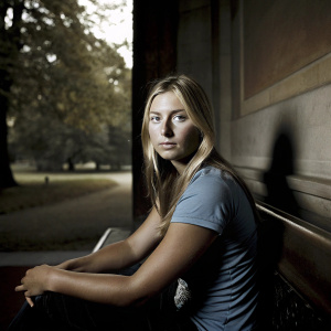 Close-up of Maria Sharapova, blonde hair cascading down her shoulders. Wearing a casual blue t-shirt. Sitting on a bench. Green park in the background