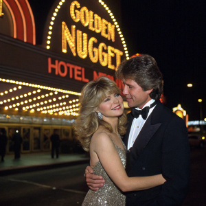 Pia Zadora and Michael Jeffries embrace at a grand casino event. The Golden Nugget Hotel & Casino sign glows behind them.