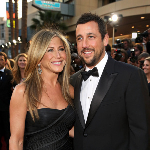 Jennifer Aniston and Adam Sandler at the bustling Hollywood premiere. Dressed in formal attire. Crowds of fans and paparazzi surround them.