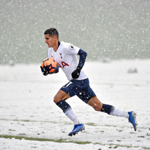Erik Lamela sprinting across a snow-covered football field, holding a soccer ball.