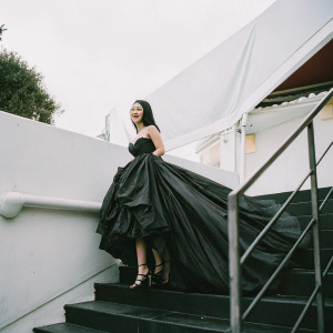 Crystal Liu Yifei at a glamorous gala. Wearing a flowing black dress with a voluminous skirt and high heels. White backdrop, beaming with a radiant smile.