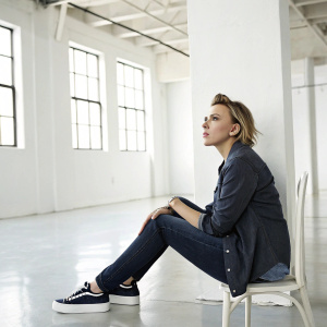 Scarlett Johansson, in casual attire, sitting alone in a minimalist studio. Bright, modern setting