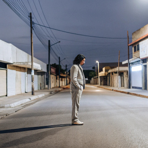Loki, dressed in modern casual attire, standing alone in a deserted street at night.