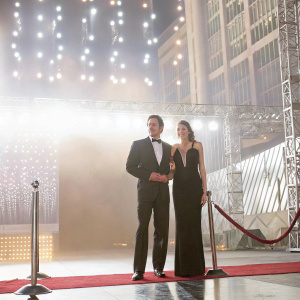 Benjamin Bratt and Talisa Soto at the Hollywood premiere. Wearing formal attire, Benjamin in tuxedo and Talisa in elegant black gown. Bright city lights in background.
