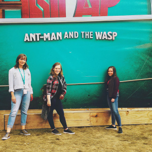 Evangeline Lilly at a film festival. Standing beside a group of young women, all wearing casual clothes. Large billboard for 'Ant-Man and the Wasp' on the wall behind them.