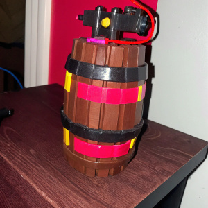 3D voxel art of C4 explosive from Fortnite. Detailed design, wooden base, mechanical parts, and barrel shape. Mixed colors of brown, gray, red, and yellow.