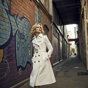 Nicole Kidman in a high-fashion photoshoot. Wearing a classic white trench coat. Urban alleyway backdrop with graffiti.