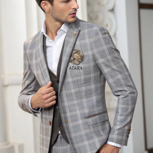 Atara wedding collection. Model adjusting a stylish gray plaid suit jacket. Tailored fit with elegant logo on chest.