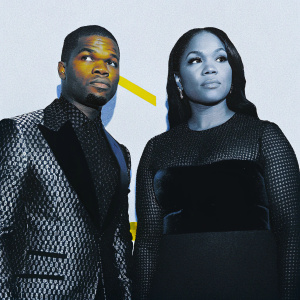 Kirk Franklin and Tammy Collins at a music awards show. Neutral expressions. Kirk in black patterned suit. Tammy in black dress with mesh overlay. White background with minimal logos.