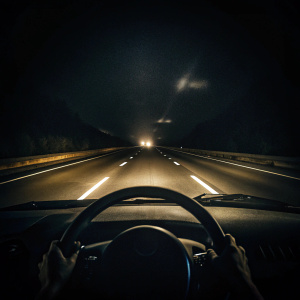 dark night journey, dark long road, angle from inside the vehicle looking at the road from the driver's seat, steering wheel on the left, the vehicle is in the right lane, headlight light only, There is no oncoming car