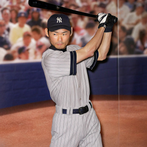 Ichiro Suzuki in batting stance, intense focus. Baseball game crowd in the background, blurred.