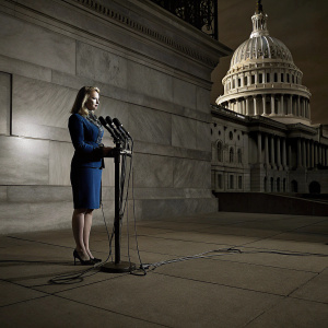 Marie Harf, in a blue suit, addressing journalists at a news conference. U.S. Capitol Building in the background.