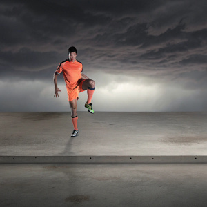 Cristiano Ronaldo in a vibrant promotional photo. Dark background, dynamic pose, athletic wear, focused expression