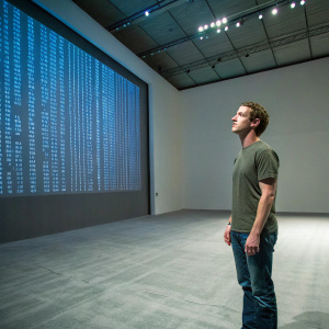 Mark Zuckerberg, CEO of Facebook, standing alone in a vast, empty room. The walls are adorned with a single large digital screen displaying complex code. He is dressed in casual attire, a green t-shirt and jeans. Solemn expression