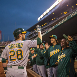 Eric Sogard, player of Oakland Athletics, cheering with teammates in dugout post-game. Gray jersey, number 28, helmet. Teammates waving, standing. Stadium background.